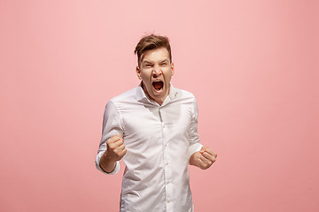 Image showing The young emotional angry man screaming on pink studio background