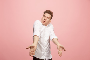 Image showing Beautiful male half-length portrait isolated on pink studio backgroud. The young emotional surprised man