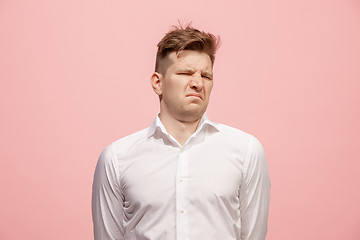 Image showing Young man with disgusted expression repulsing something, isolated on the pink