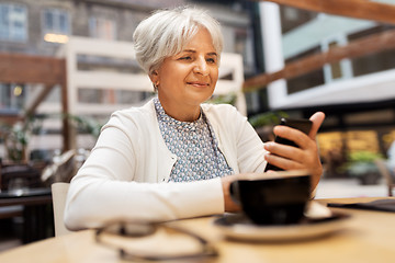 Image showing happy senior woman with smartphone at street cafe