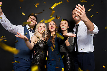 Image showing happy friends at party under confetti over black