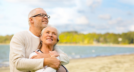 Image showing happy senior couple hugging over beach background