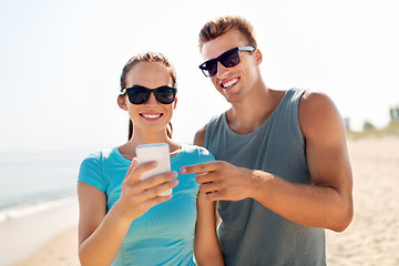 Image showing couple in sports clothes with smartphones on beach