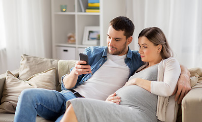 Image showing man and pregnant wife with smartphone at home