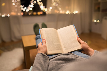 Image showing close up of young man reading book at home