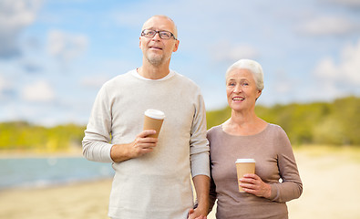 Image showing senior couple with takeaway coffee on beach