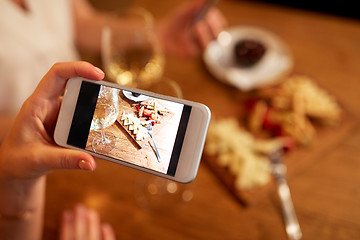 Image showing hand picturing food by smartphone at wine bar