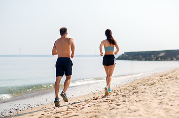 Image showing couple in sports clothes running along on beach