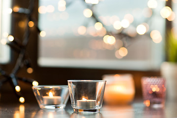 Image showing candles burning on window sill with garland lights