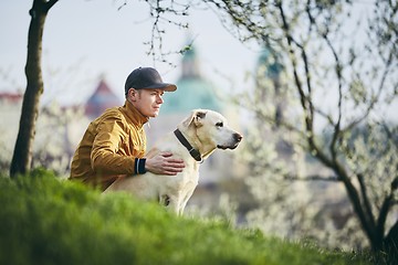 Image showing Young man relaxation with dog in public park