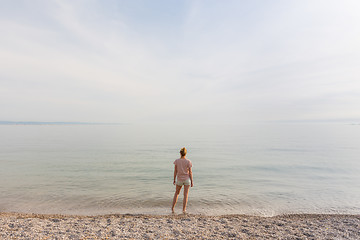 Image showing Happy Carefree Woman Enjoying Sunset Walk on White Pabbled Beach.