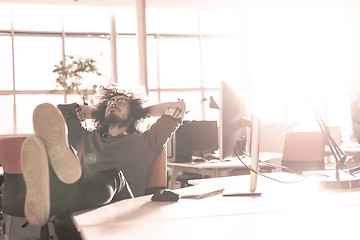 Image showing businessman sitting with legs on desk