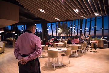 Image showing waiter standing with hands behind his back