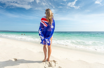 Image showing Woman standing on beach with flag wrapped around her