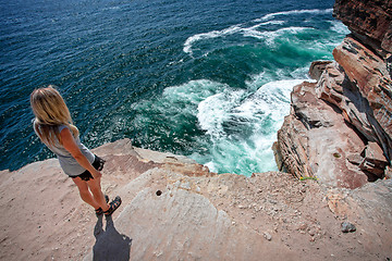 Image showing Female takes in the ocean views from cliff top ledge