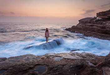 Image showing Female standing on shipwreck rock with ocean flowing over it