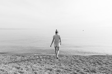 Image showing Happy Carefree Woman Enjoying Sunset Walk on White Pabbled Beach.