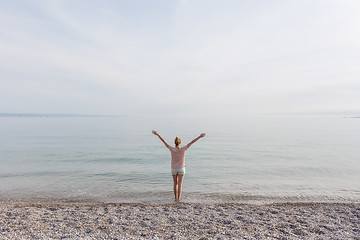 Image showing Happy Carefree Woman Enjoying Sunset Walk on White Pabbled Beach.