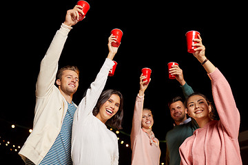 Image showing friends toasting party cups on rooftop at night