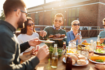 Image showing happy friends eating at barbecue party on rooftop