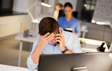 Image showing stressed man calling on smartphone at night office