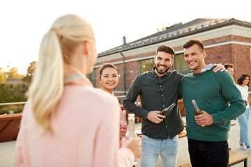 Image showing happy friends with drinks hugging at rooftop party