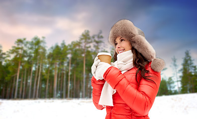 Image showing woman in fur hat with coffee over winter forest