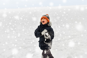 Image showing happy little boy playing with snow in winter