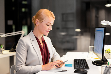 Image showing businesswoman with smartphone at night office