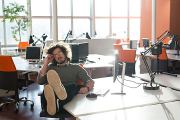 Image showing businessman sitting with legs on desk