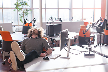 Image showing businessman sitting with legs on desk