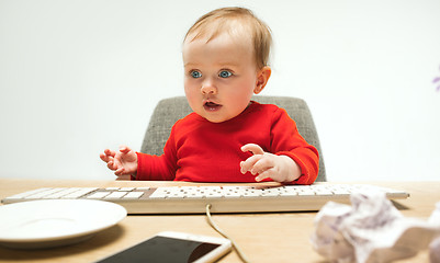 Image showing Happy child baby girl toddler sitting with keyboard of computer isolated on a white background