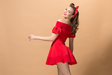 Image showing Beautiful young woman with pinup make-up and hairstyle. Studio shot on pastel background