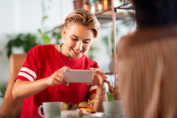 Image showing happy woman photographing cake at cafe