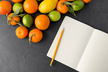 Image showing close up of fruits and notebook on slate table top