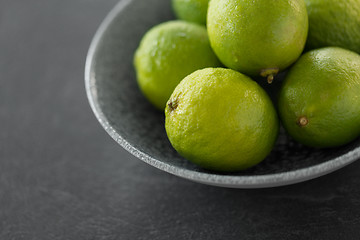 Image showing close up of whole limes in bowl on slate table top