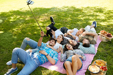 Image showing friends taking picture by selfie stick at picnic