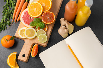 Image showing close up of fruits, juices and notebook on table