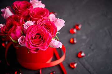 Image showing Pink roses bouquet packed in red box and placed on black stone background