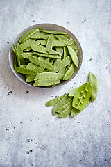 Image showing Fresh green peas in white ceramic bowl on gray stone background