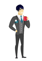 Image showing Young asian groom holding cup of coffee.