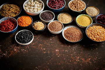 Image showing Various superfoods in smal bowls on dark rusty background