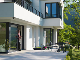 Image showing man drinking coffee in front of her luxury home villa