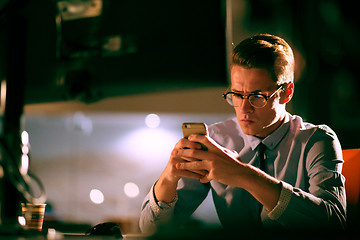 Image showing man using mobile phone in dark office