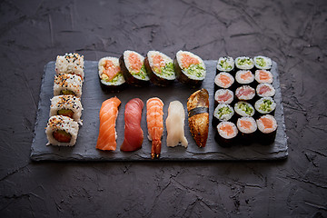 Image showing Sushi rolls set with salmon and tuna fish served on black stone board
