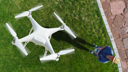 Image showing Drone Quadcopter (UAV) In Air Above Pilot With Remote Controller