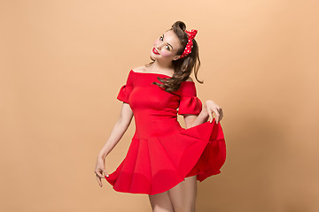 Image showing Beautiful young woman with pinup make-up and hairstyle. Studio shot on pastel background