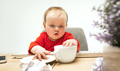 Image showing Happy child baby girl toddler sitting with keyboard of computer isolated on a white background