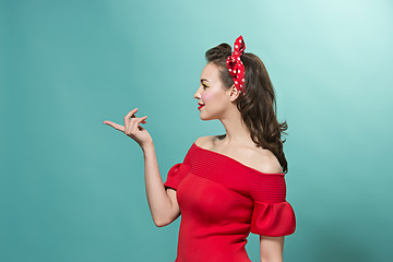 Image showing Beautiful young woman with pinup make-up and hairstyle. Studio shot on pastel background