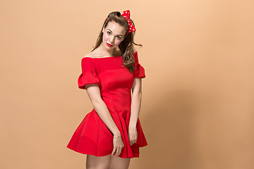 Image showing Beautiful young woman with pinup make-up and hairstyle. Studio shot on pastel background